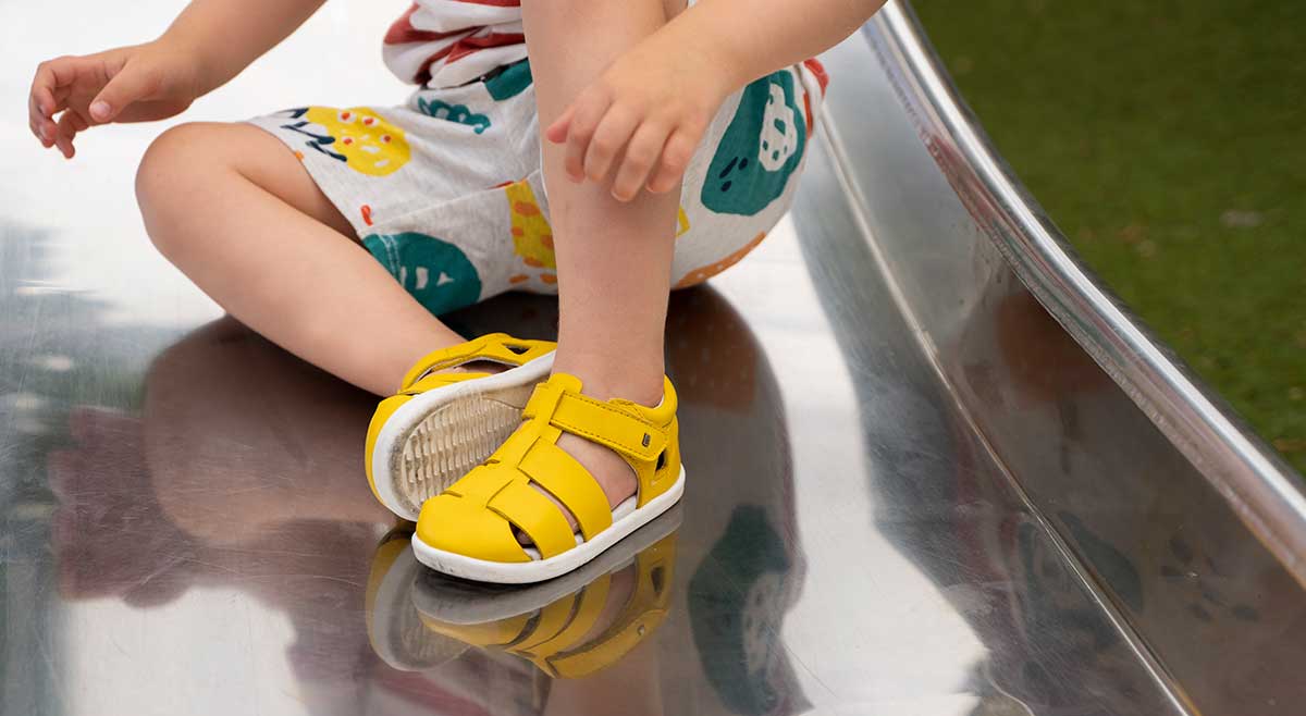 Little boy wearing yellow Playhouse shoes from Bobux