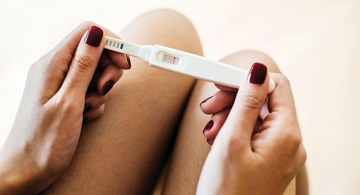 Woman Looking at Pregnancy Test Experiencing Secondary Infertility
