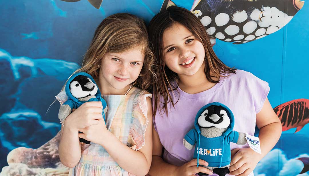 Girls with soft toy penguins at Sea Life Mooloolaba