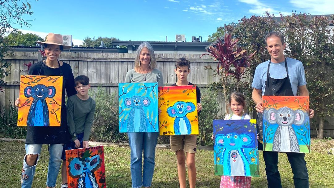 families holding up paintings at a Paint 'n' Sip session on the Sunshine Coast