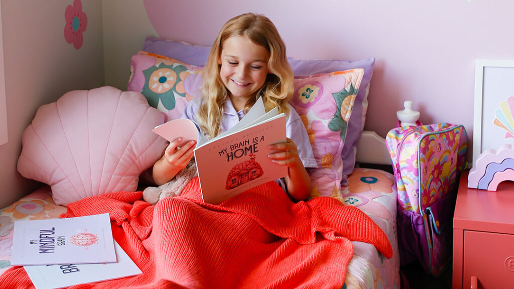 Girl Reading Book on Bed Under a Woven Woven Children's weighted blanket