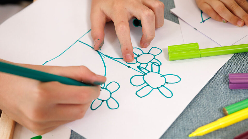 Child Drawing a Row of Flowers.