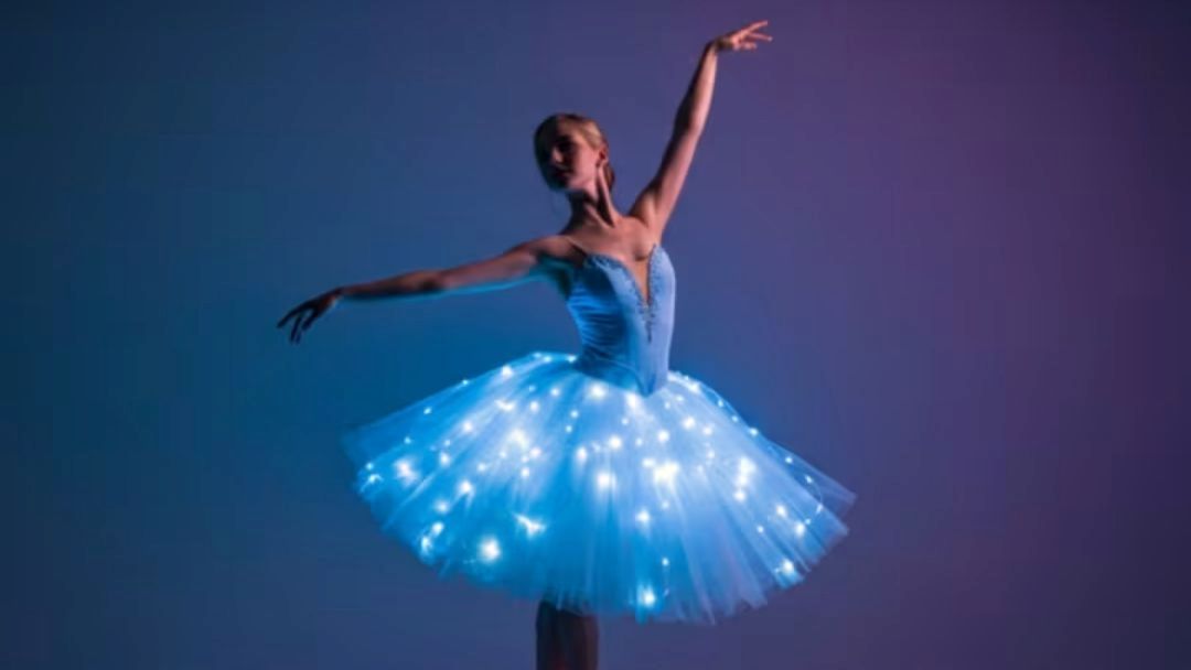 Ballerina in a blue tutu with illuminated lights on the skirt performing a graceful pose.
