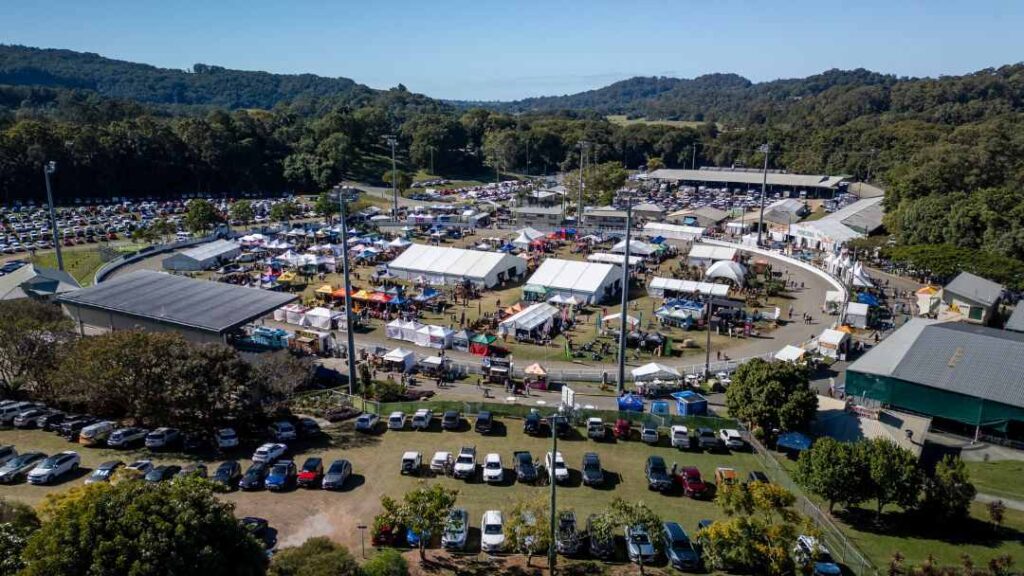 0623_queenslandgardenshow5 | Kids in Brisbane, Gold Coast, Sunshine Coast | Kotc Aerial View of a Large Outdoor Market/festival with White Tents, Vendor Booths, and Surrounding Parking on a Sunny Day.