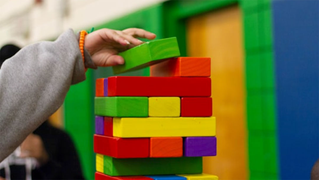 Kids-birthday-party-flowers | Kids in Brisbane, Gold Coast, Sunshine Coast | Kotc Child Stacking Bright Wooden Blocks into a Tall Tower in a Colorful Play Area.