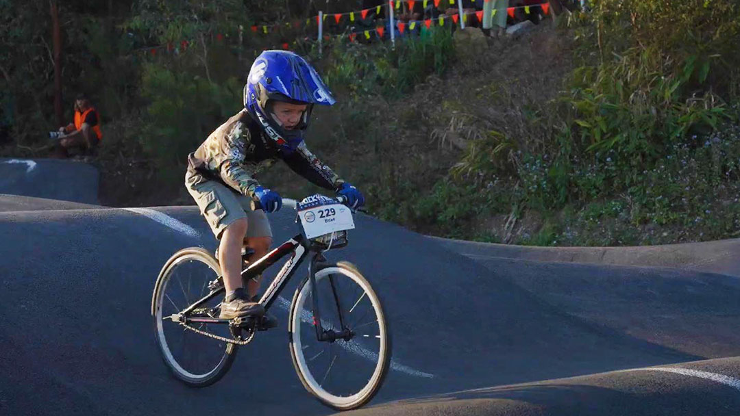 Pumped-for-the-new-coolum-pump-track | Kids in Brisbane, Gold Coast, Sunshine Coast | Kotc Child Riding Bmx Bike on a Pump Track Wearing a Blue Helmet