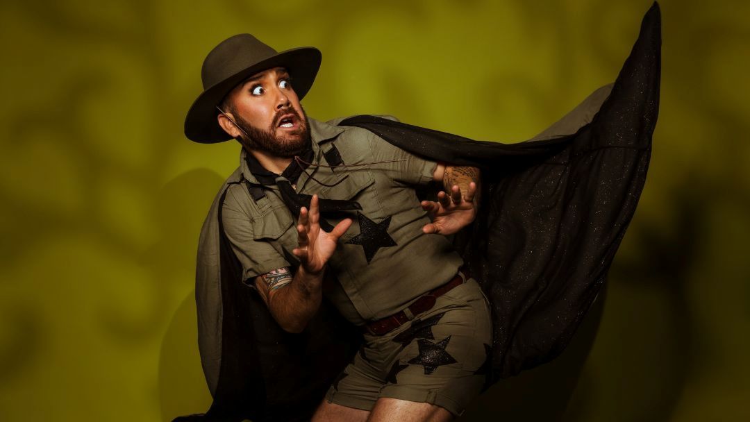 Man dressed as a ranger or cowboy with a black cape, wide-eyed and startled, reaching out as if dodging something against a yellow-green background.