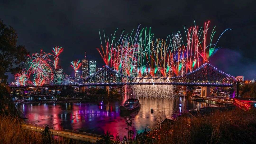 0804_brisbanefestival_2026_hero2 | Kids in Brisbane, Gold Coast, Sunshine Coast | Kotc Night Scene of Colorful Fireworks over a Lit City Skyline and a Large Arched Bridge Spanning a Calm River, with Reflections on the Water