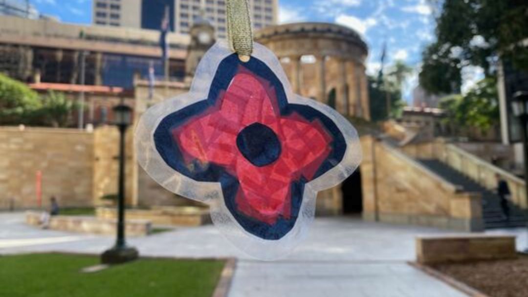 Colorful Flower-shaped Ornament Hanging in an Urban Plaza with Stone Buildings in the Background.